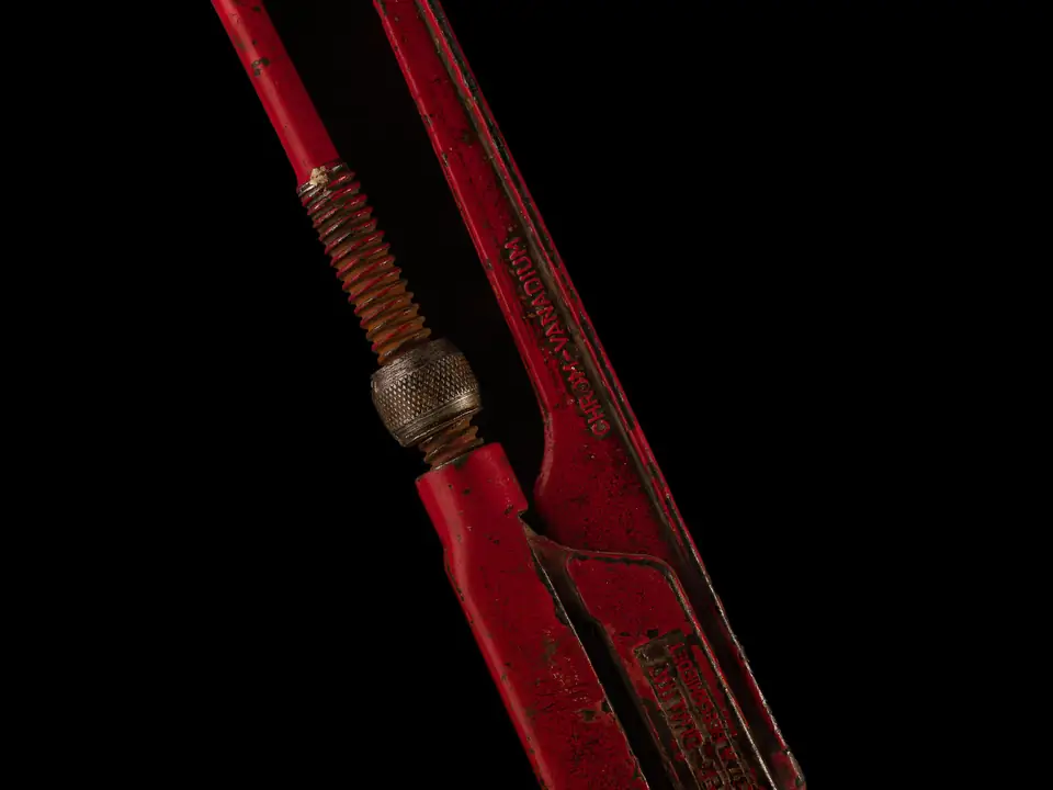Red pipe wrench on a black background